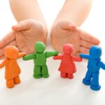 Child hands protecting clay people